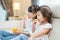 Asian Two sweet sisters little girl resting on sofa at home enjoy eating fast food, potato chips. Hungry preschool Cute kid Puts s
