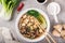 Asian vegan noodle soup with tofu cheese,shiitake mushroms and pak choi in white bowl and ingredients