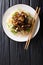 Asian vermicelli with fried eggplants and peanuts close-up on a plate. Vertical top view