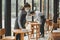 Asian waitress staff wearing protection face mask in apron cleaning table with disinfectant spray for protect infection coronaviru