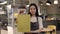 Asian waitress with takeaway order in hands standing at cafe