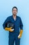 Asian welder with leather gloves holding welding helmet isolated on blue background