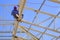 Asian welder welding metal on building roof structure in construction site against blue sky