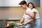 Asian Wife Hugging Husband While He Cooking Dinner In Kitchen