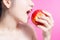 Asian woman with apple concept. She smiling and holding apple. Beauty face and natural makeup. Isolated over pink background.