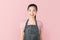 Asian woman in apron and standing and looking forward on pink background. Small business Concept.