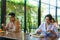 Asian woman and asian people eating food alone at table with plexi screen between table in reopening restaurant after lockdown