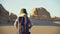 Asian woman with backpack hiking in gobi desert with yardang landforms at sunset
