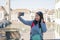 Asian woman backpacker touring in Europe - young happy and pretty Japanese girl with student backpack taking selfie with mobile