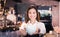 Asian woman barista smiling with a cup of coffee in her hand