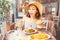 Asian woman in big hat having meal with greek salad Horiatiki in restaurant. Greece cuisine concept