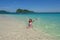 Asian woman in bikini playing in clear blue sea with splashing on island beach