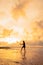 An Asian woman in a black dress performs ballet movements beautifully on the beach with waves and clouds behind her