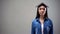 Asian woman with book on head standing on grey background, university student