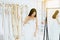 Asian woman bride trying on white wedding dress in room