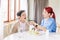 Asian woman caregiver wearing medical scrub takes care of senior Asian woman by feeding vegetarian salad to eat at home.