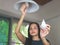 Asian woman  changing light bulb in her house. replace fluorescent to LED  light bulb, showing LED light bulb to camera..