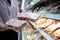 Asian woman chooses smoked ham in a vacuum package,selecting food quality,hygienic,female purchasing sausages pack in refrigerator