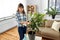 Asian woman cleaning houseplant by tissue at home