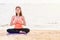 Asian woman close eyes and doing Hand namaste yoga pose and meditates on sand at coastline beach, Calm and relax