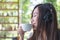 Asian woman close her eyes and listening to music with headphone while drinking coffee with feeling happy and relax in cafe with g