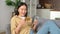 Asian woman consumer holding credit card and smartphone sitting on sofa