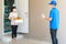 Asian woman costumer wearing face mask and glove receive groceries box of food, fruit, vegetable and drink from delivery man   in