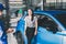 Asian woman customer smiling with blue car in dealership service maintenance insurance and receives the keys from the mechanic