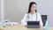 Asian woman doctor with black long hair in white lab coat working on her tablet