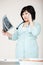 Asian woman doctor in robe discussing diagnosis talking on phone, considering X-ray picture. Medical mistake, the