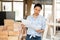 Asian woman with documents in her hands stands in the middle of renovated room in cottage.