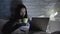 Asian woman drinking coffee working on laptop late in bedroom, meeting deadline