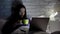 Asian woman drinking coffee working on laptop late in bedroom, meeting deadline