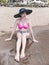 An asian woman in an elegant two-piece swimsuit sits on the beach right by the foreshore. In deep thought or slightly worried