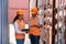 asian woman Engineer with note clipboard and asian man Supervisor in Hard Hats and Safety Vests Stand in Container Terminal.