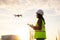 Asian woman engineer operate flying drone over oil refinery plant during sunrise building site survey in civil engineering project