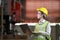 Asian woman engineering manager in safety hard hat and reflective cloth is inspecting inside the factory using digital laptop