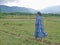 Asian woman enjoys walking in a field in a rural area - getting outside and engage with nature provides positive impact on health