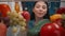 An Asian woman examines a refrigerator filled with healthy products: vegetables, fruits, berries. Satisfied woman nods