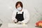 Asian woman with a face mask and gloves slicing a peeled onion on a cutting board at a kitchen