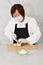 Asian woman with face mask and gloves using a kitchen knife to slice an onion on a cutting board