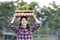 Asian woman farmer is carrying the wooden tray full of freshly pick organics vegetables over her head at the garden for harvest
