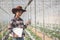 Asian woman farmer using tablet and notebook for research and check the quality of the melon tree in the  greenhouse