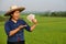 Asian woman farmer wears hat, blue shirt, holds Thai banknote money