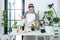 Asian woman gardener in casual clothes, watering plants in ceramic pots with watering can after transplanting