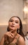 an Asian woman with a gold necklace and earrings is posing beautifully in a hotel room before dinner