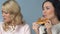 Asian woman greedily eating pizza in front of her friend who keeping diet