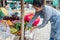 Asian woman greengrocer bent over to arrange tempeh for a vegetable stall