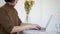 Asian woman half face headshot short haircut working with laptop with flowers in vase
