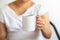 Asian woman hand holding a white cup of mug of hot black Americano coffee